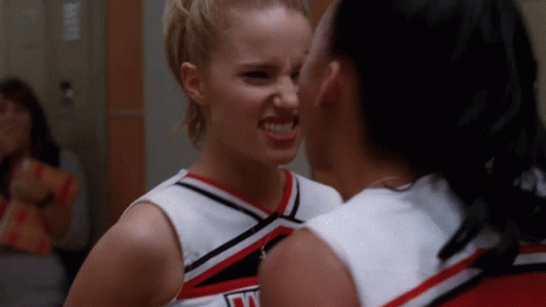 Two Cheerleaders Looking at Each Other, One Wearing Jersey Saying N