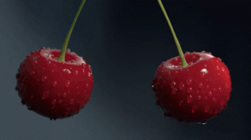 Two Cherries Are Being Splashed With Water Against A Dark Background GIF