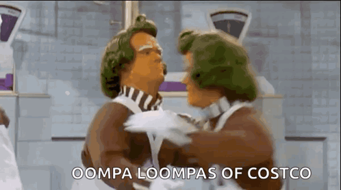 Two Chocolate Men Are Hugging Each Other In A Kitchen And The Words Oompa Loompas Of Costco Are Visible . GIF