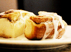 Two Cinnamon Rolls On A White Plate With Icing On Them GIF