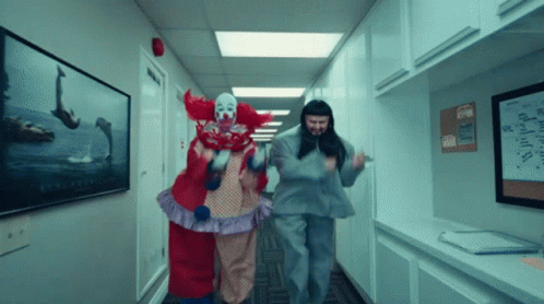 Two Clowns Are Walking Down A Hallway With A Lego Sign On The Wall Behind Them GIF
