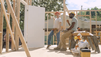 Two Construction Workers Are Having A Conversation While Sitting On A Stool GIF