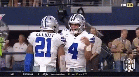 Two Cowboys Football Players Are Hugging Each Other In The Stands GIF