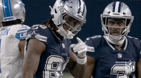 Two Cowboys Football Players Are Standing Next To Each Other On The Field And Pointing At Each Other . GIF