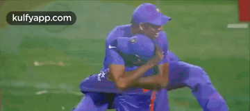 Two Cricket Players Hugging Each Other On A Field GIF