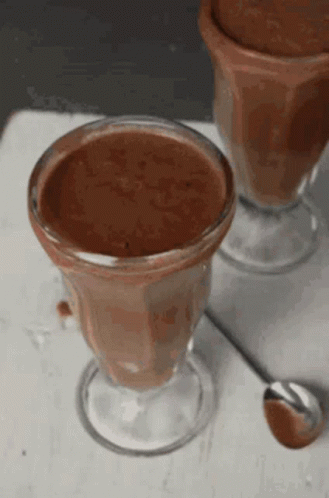 Two Cups Of Chocolate Mousse With A Spoon In Them GIF