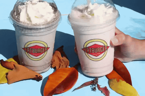 Two Cups Of Milkshakes From Fatburger Are On A Table GIF
