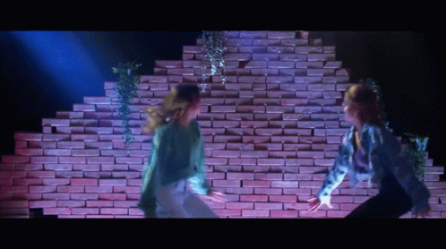 Two Dancers Dancing in Front of Brick Wall