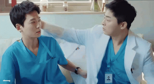 Two Doctors In Scrubs Are Talking To Each Other In A Hospital Room GIF