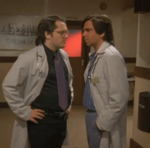 Two Doctors Shaking Hands by Emergency Room Sign