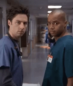 Two Doctors Standing Next To Each Other In A Hospital Hallway . GIF