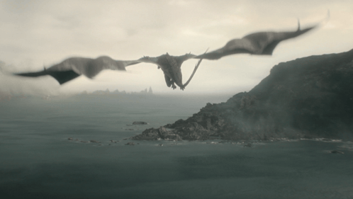 two dragons are flying over a body of water with mountains in the background