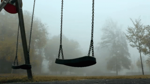 Two Empty Swings In A Foggy Park On A Cloudy Day GIF