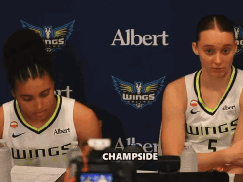 Two Female Basketball Players Are Sitting In Front Of A Banner That Says Albert Champside GIF