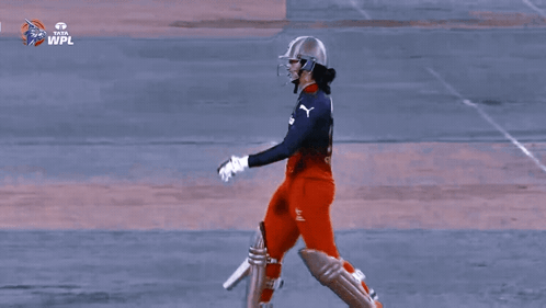 Two Female Cricket Players Standing Next To Each Other With Their Bats In Front Of A Tata Advertisement GIF