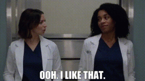 Two Female Doctors Are Standing Next To Each Other In A Hallway And One Of Them Is Talking . GIF