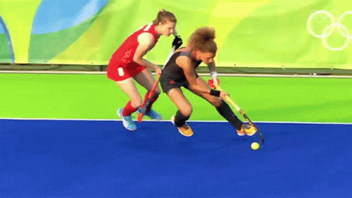 Two Female Field Hockey Players Are Playing On A Field GIF