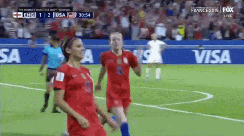 Two Female Soccer Players Are Running On The Field During A Match Sponsored By Visa . GIF