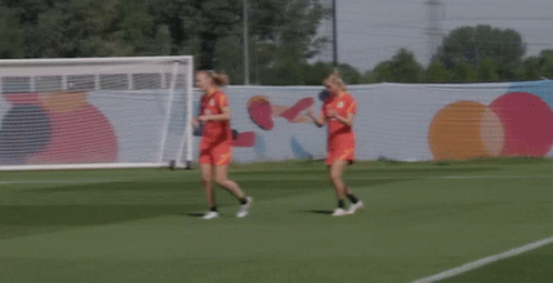 two female soccer players running on a field