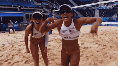Two Female Volleyball Players From The Usa Are Standing On The Sand GIF