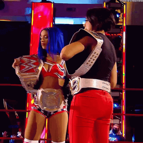 Two Female Wrestlers Holding Belts in Ring