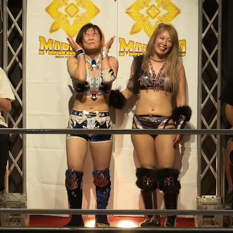 Two Female Wrestlers Stand In Front Of A Wall That Says Mad GIF