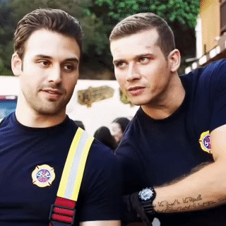 two firefighters are standing next to each other and one has a tattoo on his arm that says ' i love you '