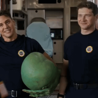two firefighters are standing next to each other holding a large green object