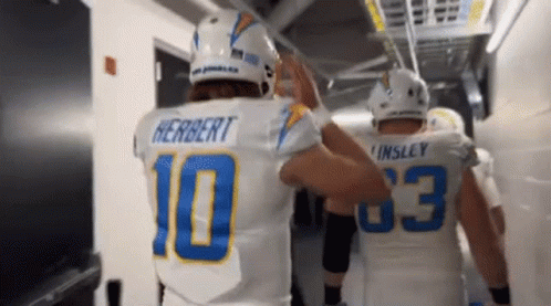 Two Football Players Are Giving Each Other A High Five In A Tunnel . GIF