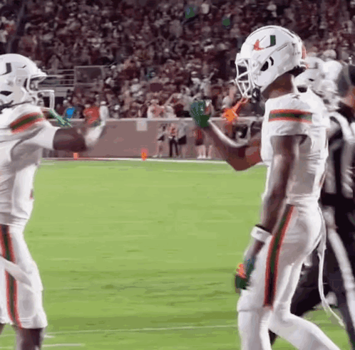 two football players are giving each other high fives on the field .