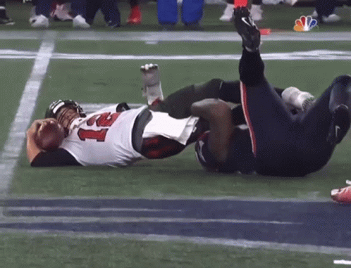 Two Football Players Are Laying On The Field With One Wearing A Jersey With The Number 22 On It GIF