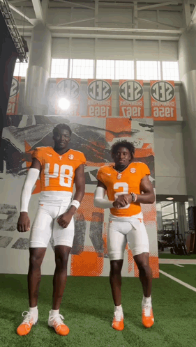 Two Football Players in Front of Wall Banner Saying Taer
