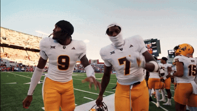 two football players one wearing number 9 and the other wearing number 7 walk off the field