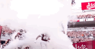 Two Football Players Running From Stadium Smoke