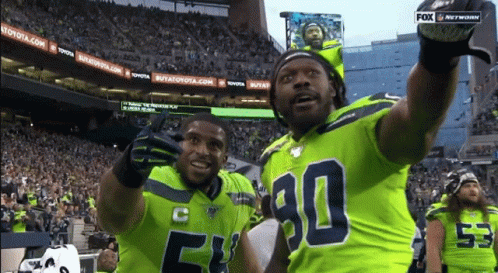 Two Football Players Wearing Green Jerseys With The Number 90 On Them GIF