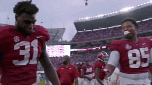 Two Football Players Wearing Red Jerseys With 31 And 95 On Them GIF