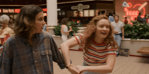 Two Girls Are Dancing In A Mall In Front Of A Sign That Says Credit Course GIF