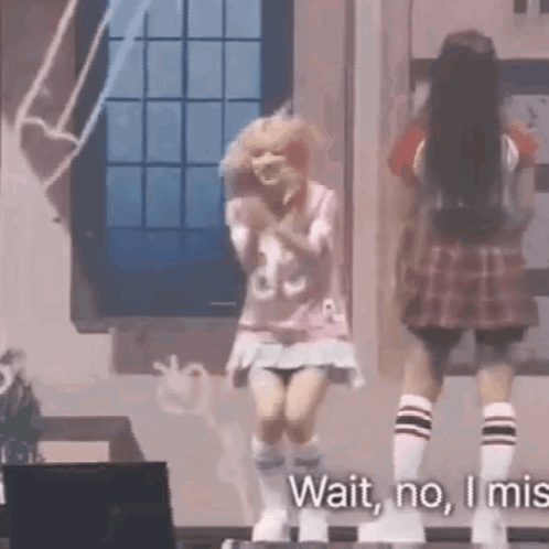 Two Girls Are Dancing On A Stage And One Of Them Is Wearing A Plaid Skirt And Socks . GIF