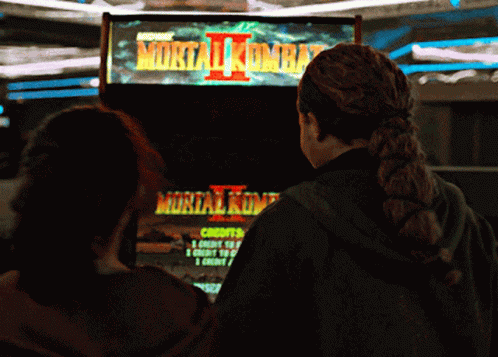 Two Girls Are Playing A Video Game Called Mortal Kombat 2 GIF