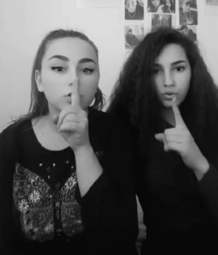 Two Girls Are Posing For A Picture And One Is Holding Her Finger To Her Lips GIF