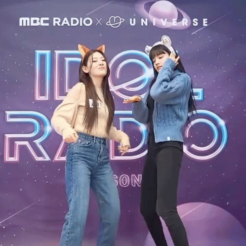 Two Girls Are Posing In Front Of A Mbc Radio X Universe Sign GIF