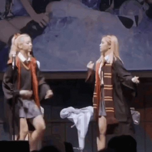 Two Girls Dressed In Harry Potter Costumes Are Dancing On Stage GIF