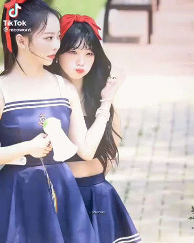 Two Girls In Blue Dresses Standing On Sidewalk GIF