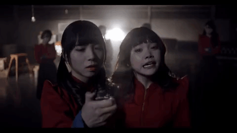 Two Girls In Red Jackets Standing In Dark Room GIF