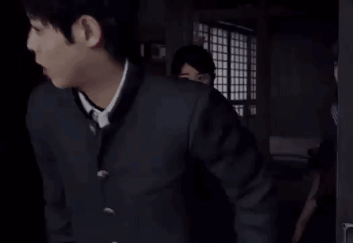 two girls in school uniforms are standing in a dark room .