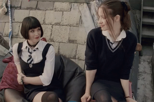 Two Girls In School Uniforms Sitting Next To Each Other GIF