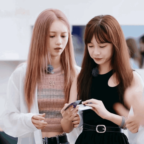 Two Girls Looking At Phone With Letter G On Belt