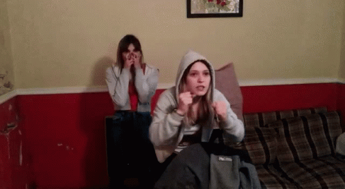 Two Girls on Couch One Wearing Hoodie
