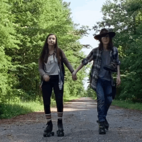 Two Girls Rollerblading On A Road Holding Hands GIF