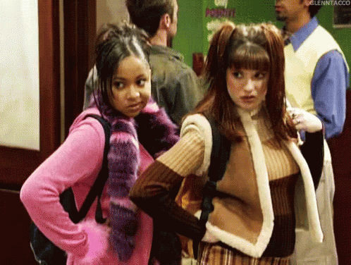 Two Girls Standing In Hallway With Man In Background GIF